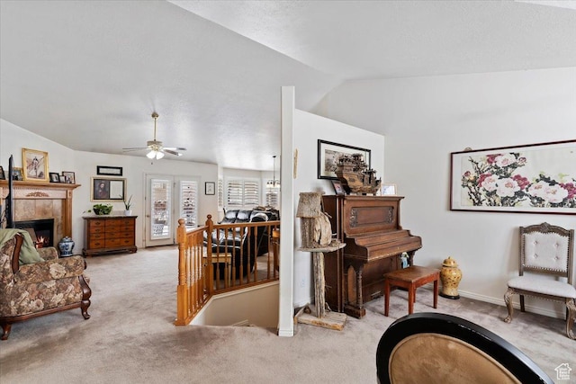 living area featuring vaulted ceiling, an upstairs landing, light colored carpet, a ceiling fan, and a fireplace