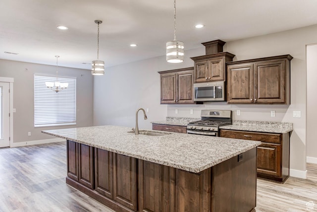 4386 W 3800 S, West Haven, UT 84401 - kitchen featuring an island with sink, light stone countertops, stainless steel appliances, light wood-style floors, and a sink