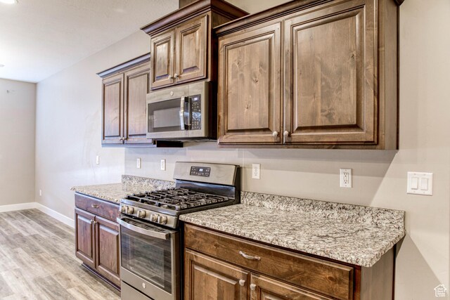 4386 W 3800 S, West Haven, UT 84401 - kitchen featuring stainless steel appliances, light wood-style floors, baseboards, and light stone countertops
