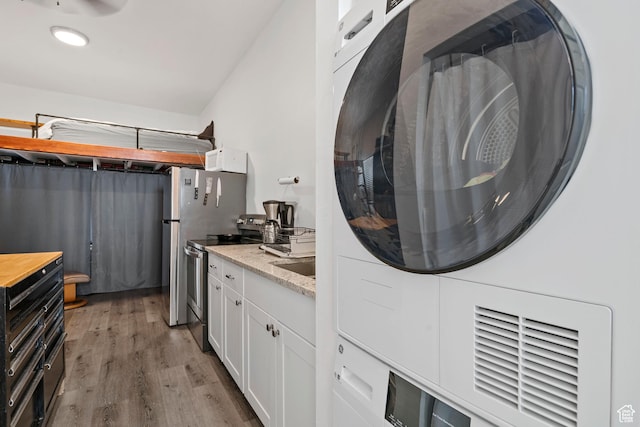 137 E Wentworth Ave, South Salt Lake, UT 84115 - laundry room with laundry area, stacked washer and clothes dryer, a sink, and wood finished floors