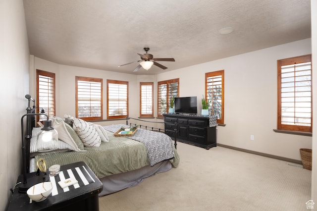 bedroom featuring a textured ceiling, baseboards, a ceiling fan, and light colored carpet