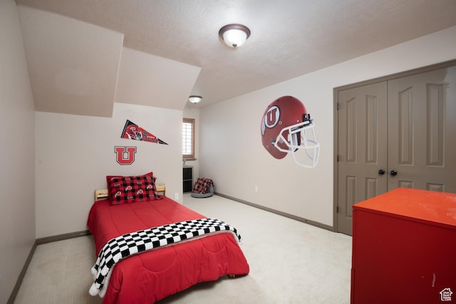 bedroom featuring carpet floors, a closet, a textured ceiling, and baseboards