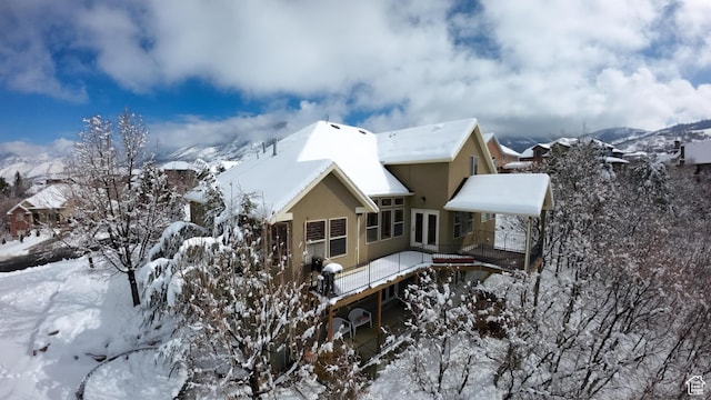 snow covered property with a mountain view and stucco siding