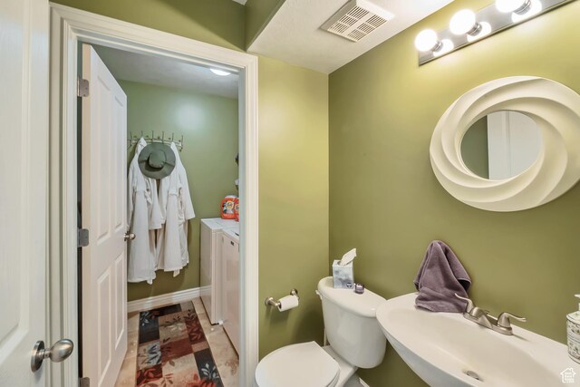 8783 N Franklin Dr, Eagle Mountain, UT 84005 - half bathroom featuring toilet, visible vents, independent washer and dryer, and a sink