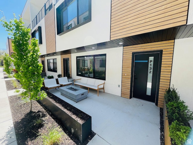 back of house featuring a patio area, stucco siding, and a fire pit
