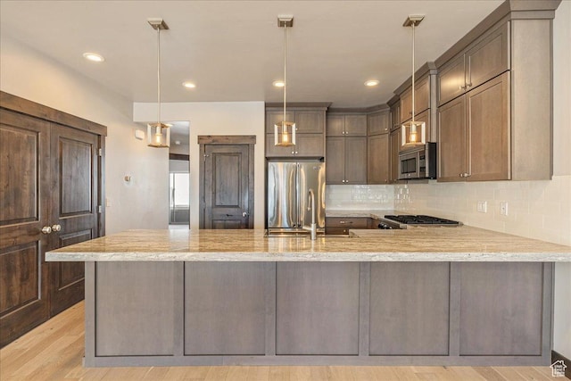 14408 N Buck Horn Trl N Unit 52C, Kamas, UT 84036 - kitchen featuring a peninsula, a sink, appliances with stainless steel finishes, backsplash, and pendant lighting