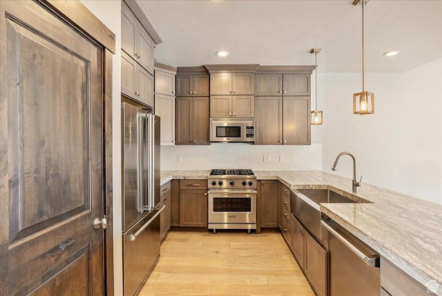 14408 N Buck Horn Trl N Unit 52C, Kamas, UT 84036 - kitchen featuring premium appliances, light stone counters, decorative light fixtures, a peninsula, and light wood-type flooring