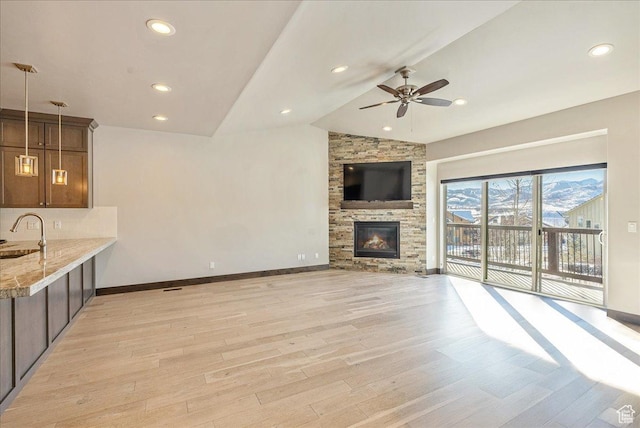 14408 N Buck Horn Trl N Unit 52C, Kamas, UT 84036 - unfurnished living room with light wood-style flooring, vaulted ceiling, a sink, a stone fireplace, and baseboards