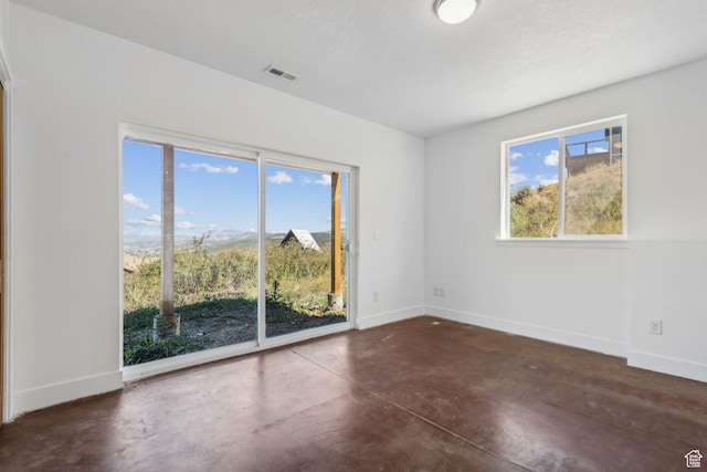 unfurnished room featuring concrete flooring, visible vents, and baseboards
