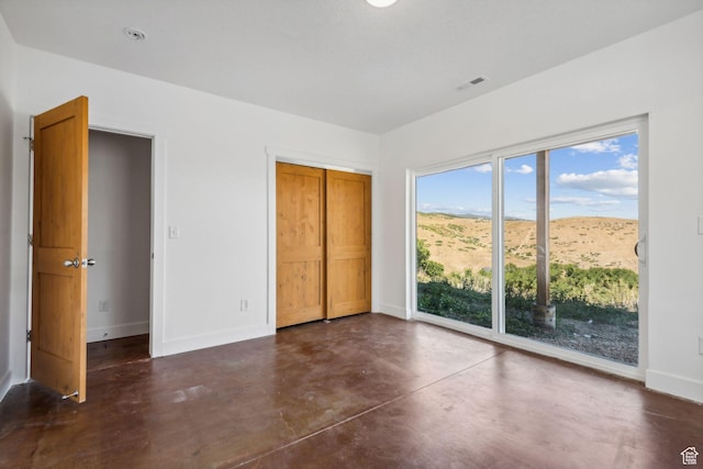 unfurnished bedroom featuring access to exterior, visible vents, a mountain view, concrete floors, and baseboards
