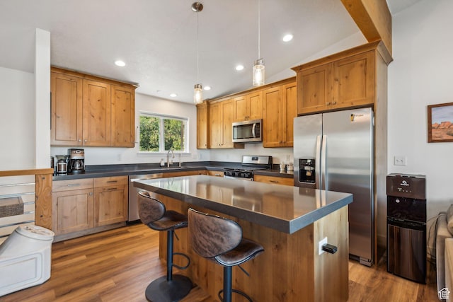 kitchen with dark wood finished floors, dark countertops, a kitchen island, hanging light fixtures, and stainless steel appliances