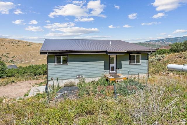 back of property with metal roof and a mountain view