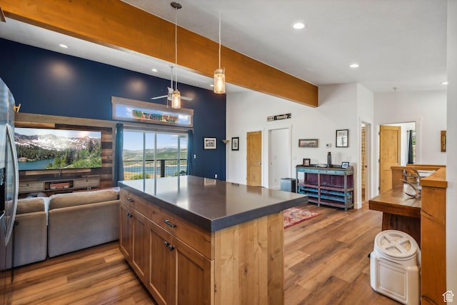 kitchen with dark countertops, brown cabinetry, open floor plan, and wood finished floors