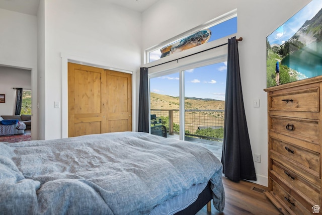 bedroom featuring access to exterior, wood finished floors, visible vents, and multiple windows