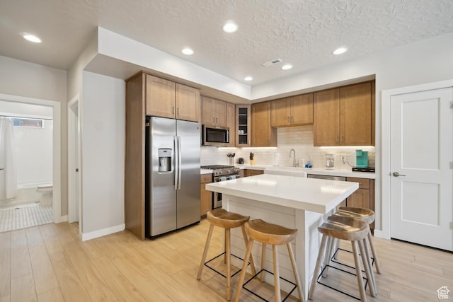 6698 Purple Poppy Ln Unit 11, Park City, UT 84098 - kitchen with appliances with stainless steel finishes, light wood-type flooring, a kitchen bar, and brown cabinets