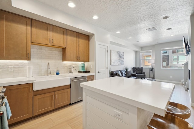 6698 Purple Poppy Ln Unit 11, Park City, UT 84098 - kitchen featuring light wood-style flooring, brown cabinetry, a sink, dishwasher, and a kitchen bar