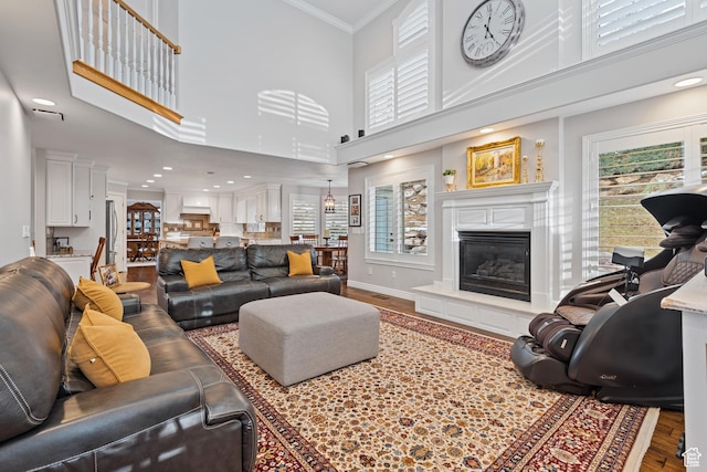 34 N Scenic Hills Cir E, North Salt Lake, UT 84054 - living area with healthy amount of natural light, wood finished floors, a towering ceiling, a glass covered fireplace, and ornamental molding