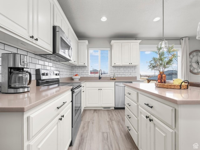 1463 S Lake View Terrace Rd, Saratoga Springs, UT 84045 - kitchen featuring white cabinets, stainless steel appliances, light countertops, and decorative light fixtures