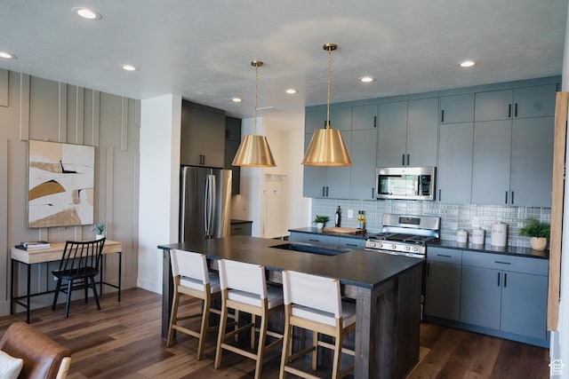 kitchen featuring stainless steel appliances, dark wood-style flooring, hanging light fixtures, decorative backsplash, and dark countertops