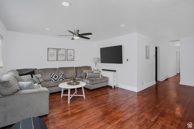 living area featuring dark wood-type flooring, a ceiling fan, and baseboards