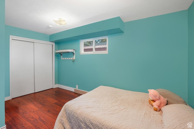 bedroom with dark wood-style floors, a closet, and baseboards