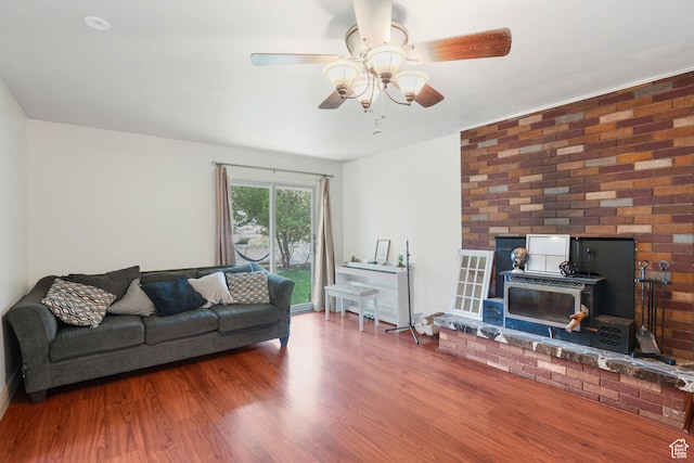 living area with ceiling fan, wood finished floors, and a wood stove