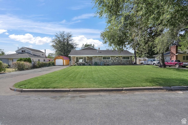 single story home with a detached garage, an outdoor structure, stone siding, driveway, and a front yard