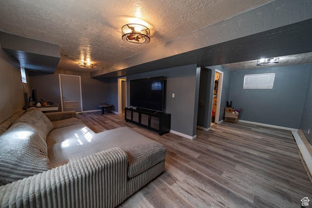 home theater room with a textured ceiling, baseboards, and wood finished floors