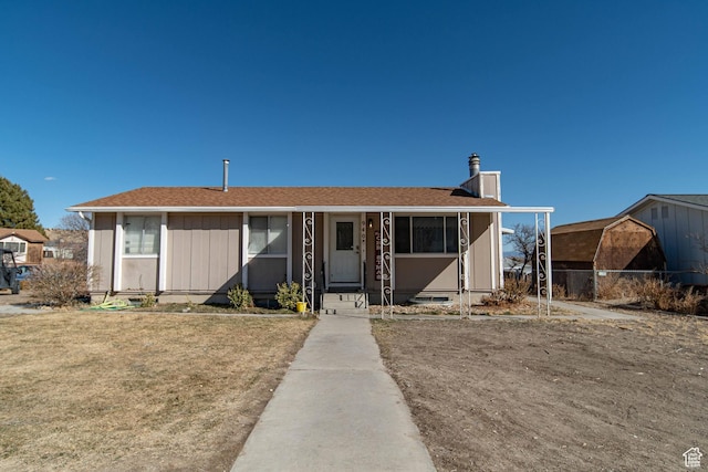 view of front of house featuring a front yard, roof with shingles, and a chimney