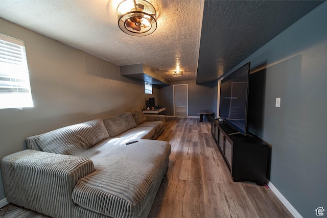 living room with a textured ceiling, baseboards, and wood finished floors