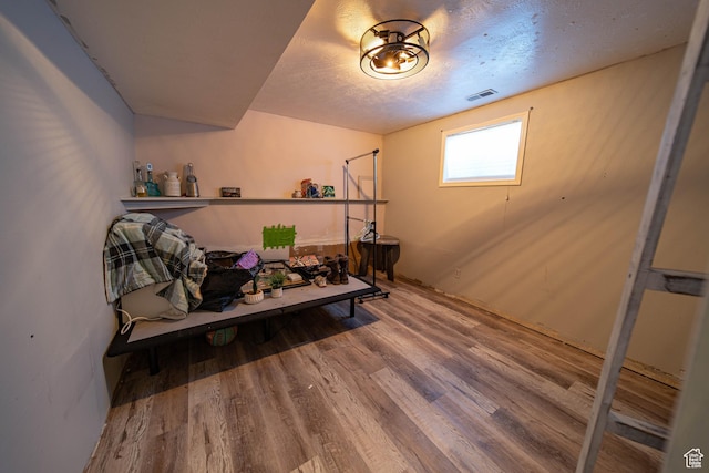 workout room with a textured ceiling, visible vents, and wood finished floors