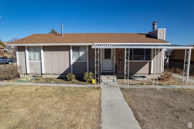 view of front of house featuring a shingled roof, a front yard, and a chimney