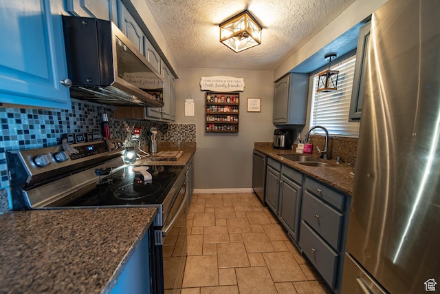 kitchen featuring stainless steel appliances, hanging light fixtures, backsplash, a sink, and baseboards