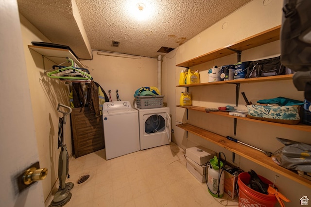 clothes washing area featuring a textured ceiling, light floors, washing machine and dryer, and laundry area