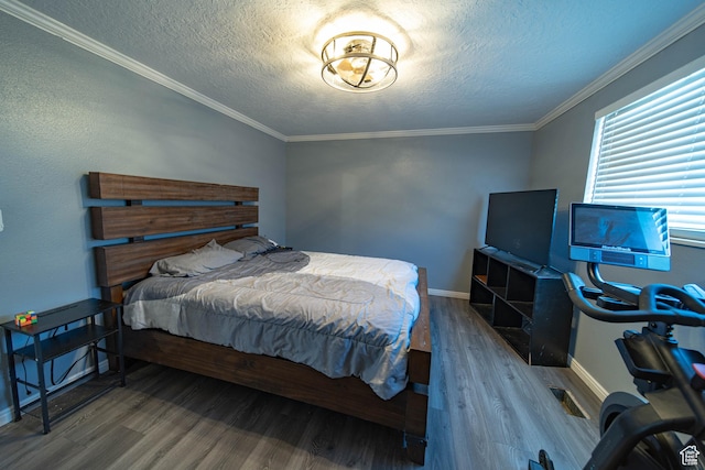 bedroom with a textured ceiling, ornamental molding, wood finished floors, and baseboards