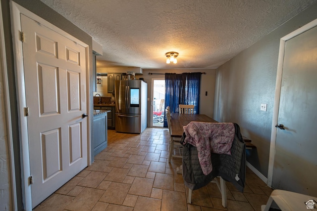 dining room with a textured wall, a textured ceiling, and baseboards