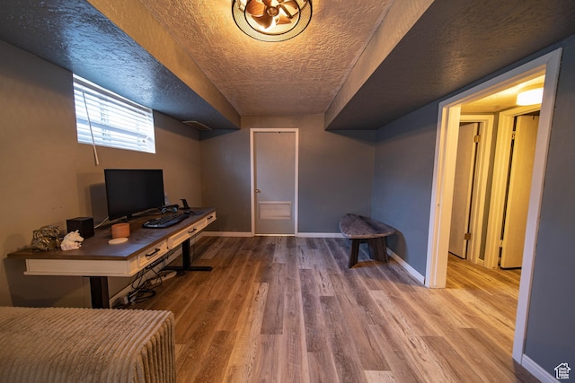 home office with a textured ceiling, baseboards, and wood finished floors