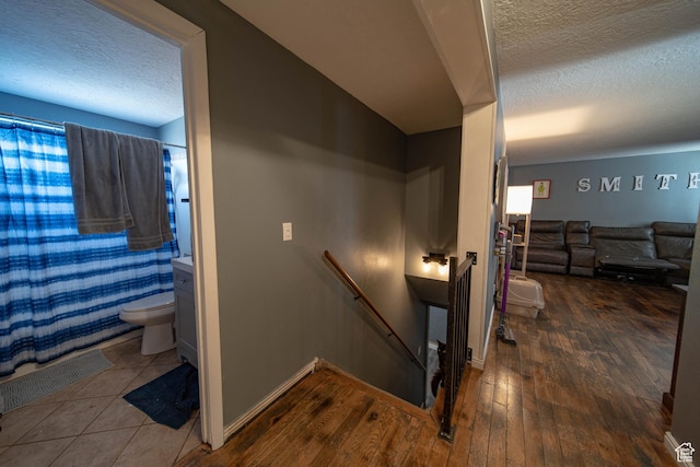 stairs with a textured ceiling, baseboards, and wood finished floors