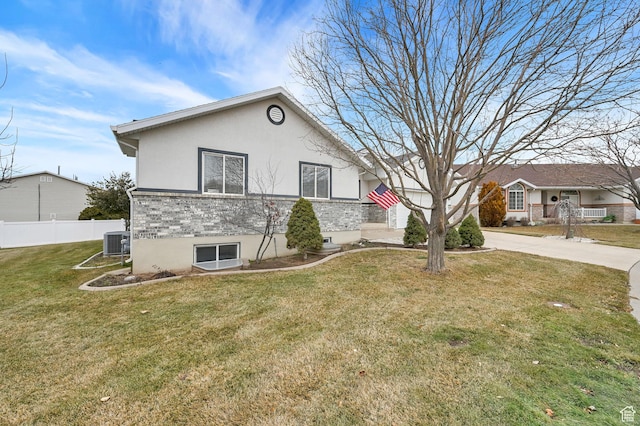 view of front of property with concrete driveway, fence, cooling unit, a front lawn, and brick siding