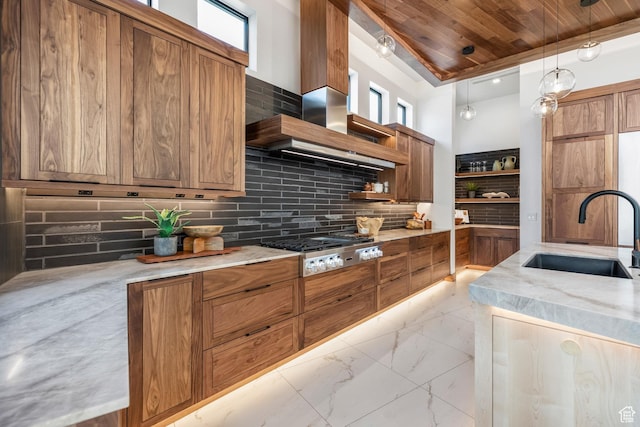 kitchen with light stone counters, decorative light fixtures, marble finish floor, stainless steel gas stovetop, and a sink