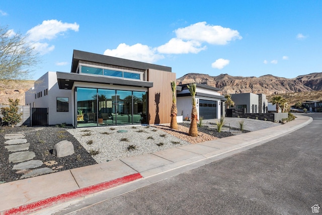 modern home featuring a garage, a mountain view, driveway, and stucco siding