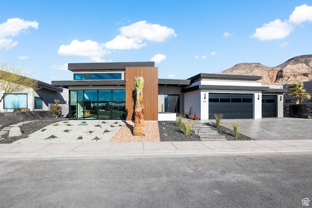 modern home with an attached garage, driveway, a mountain view, and stucco siding