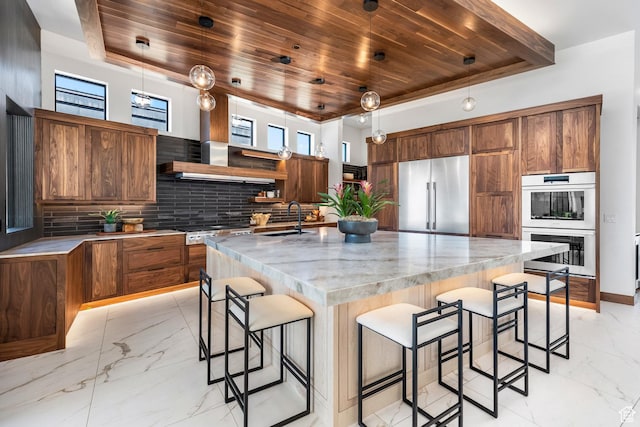 kitchen featuring marble finish floor, stainless steel appliances, a kitchen island with sink, and decorative light fixtures