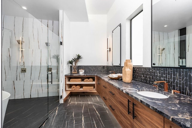 bathroom with double vanity, a marble finish shower, a sink, marble finish floor, and backsplash