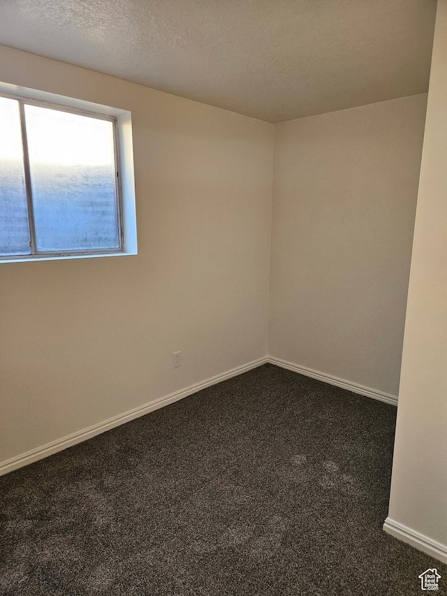 spare room with a textured ceiling, carpet floors, and baseboards