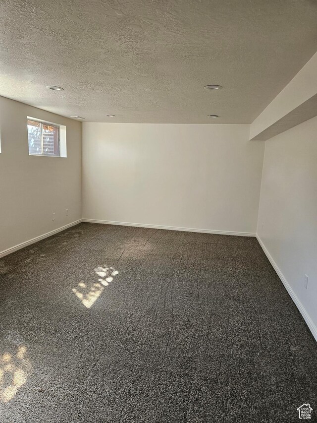 basement with carpet floors, baseboards, and a textured ceiling