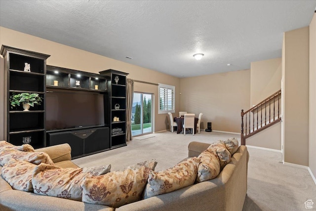 living area with light carpet, a textured ceiling, stairs, and baseboards