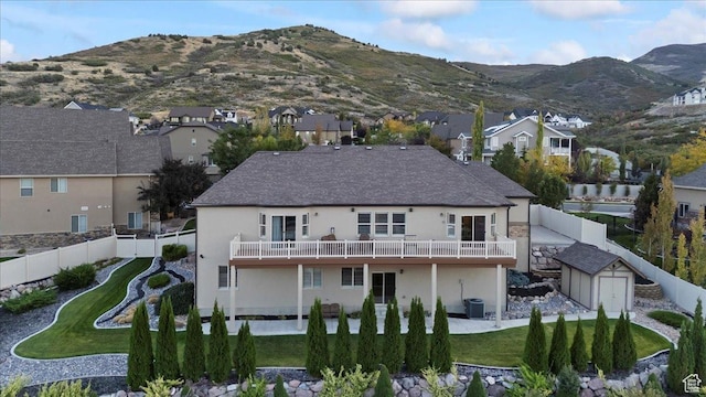 back of house with a storage shed, a fenced backyard, an outdoor structure, central air condition unit, and a mountain view