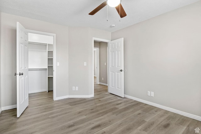 8475 S 1520 W, West Jordan, UT 84088 - unfurnished bedroom with baseboards, ceiling fan, a walk in closet, and light wood-style floors