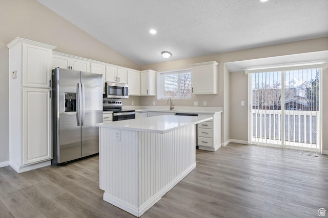 8475 S 1520 W, West Jordan, UT 84088 - kitchen with stainless steel appliances, white cabinets, vaulted ceiling, a sink, and a kitchen island